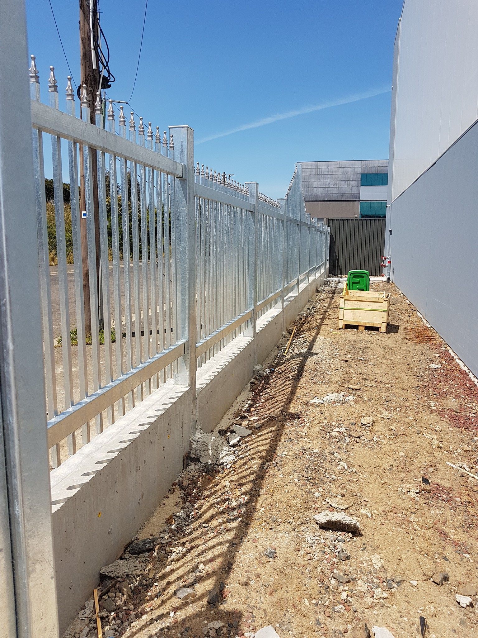 A metal fence is being built next to a building.
