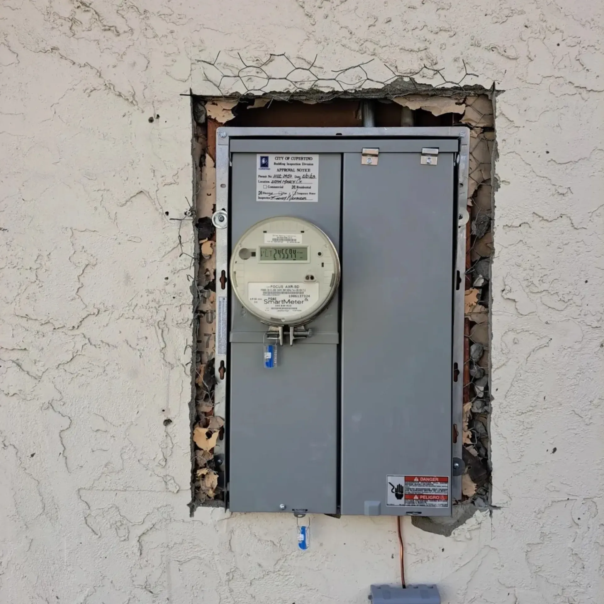 OE Services LLC - A meter on the side of a building with a warning sign on it