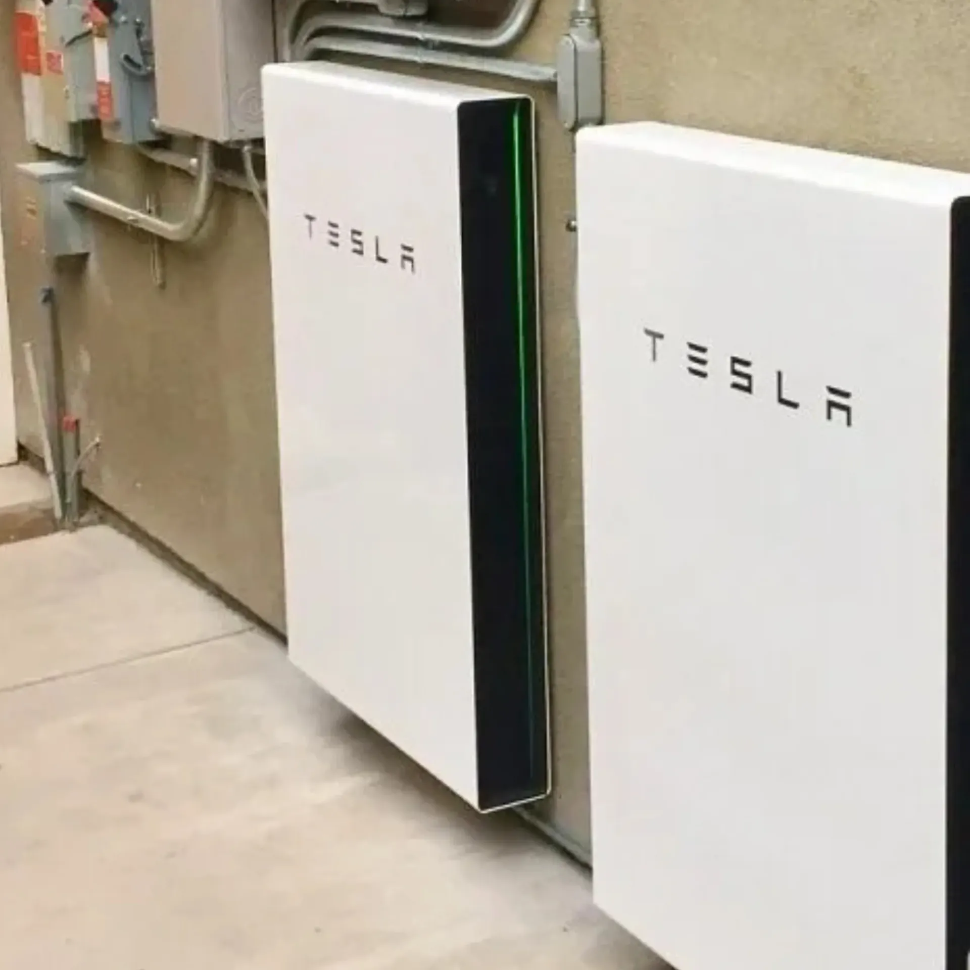 OE Services LLC - Two white tesla batteries are sitting next to each other on a wall