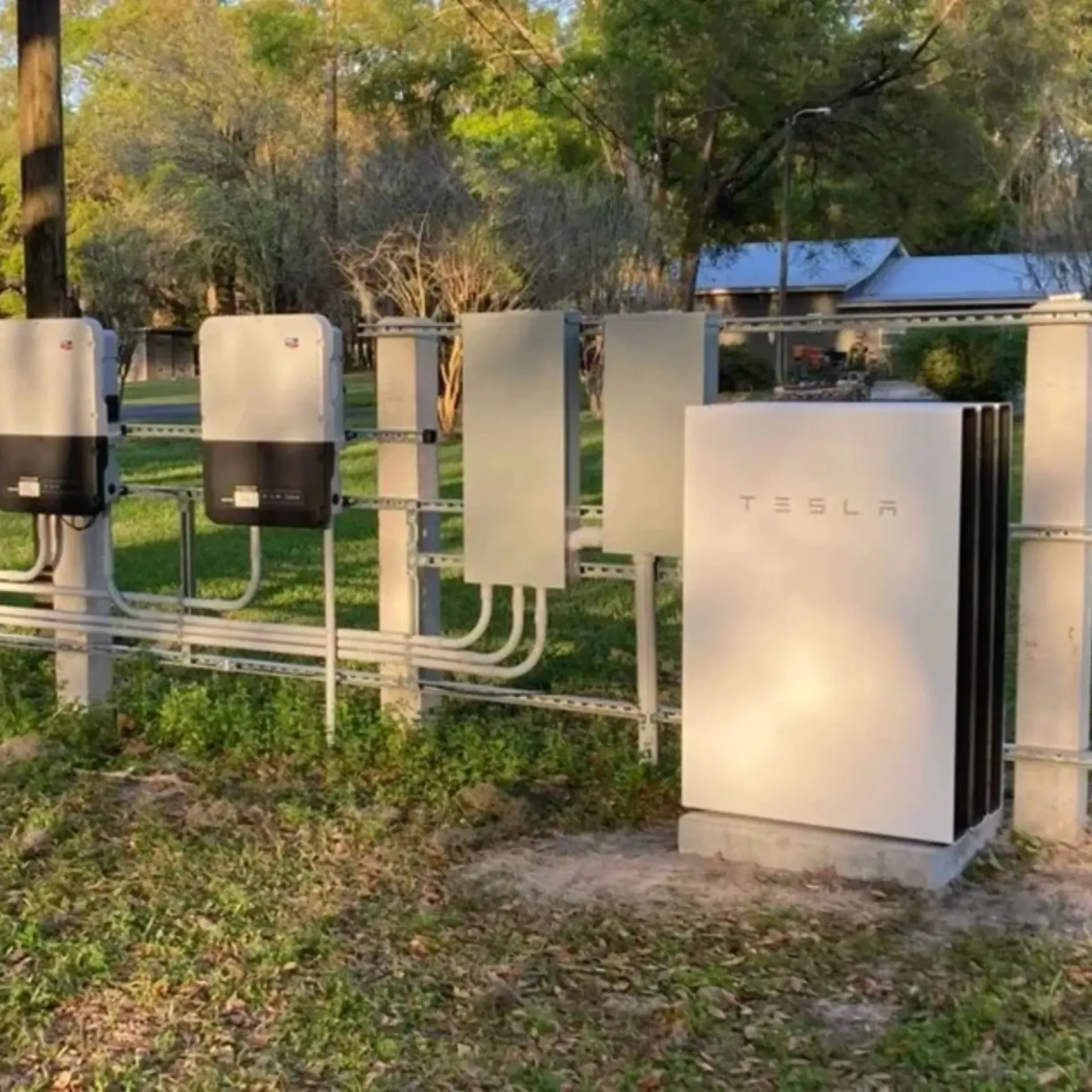OE Services LLC - A row of tesla solar panels are sitting in the grass.