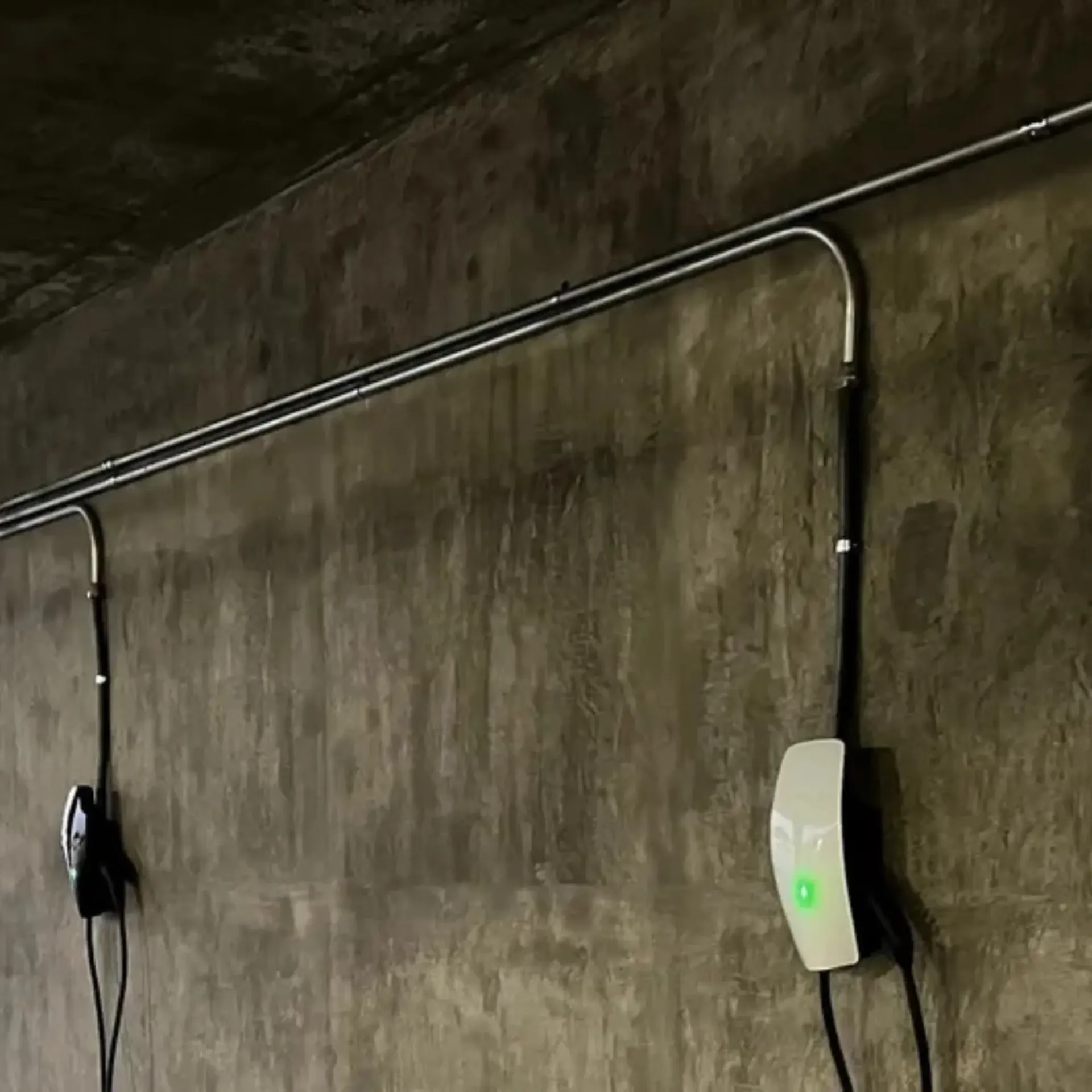 OE Services LLC - Two electric car chargers are connected to a concrete wall.