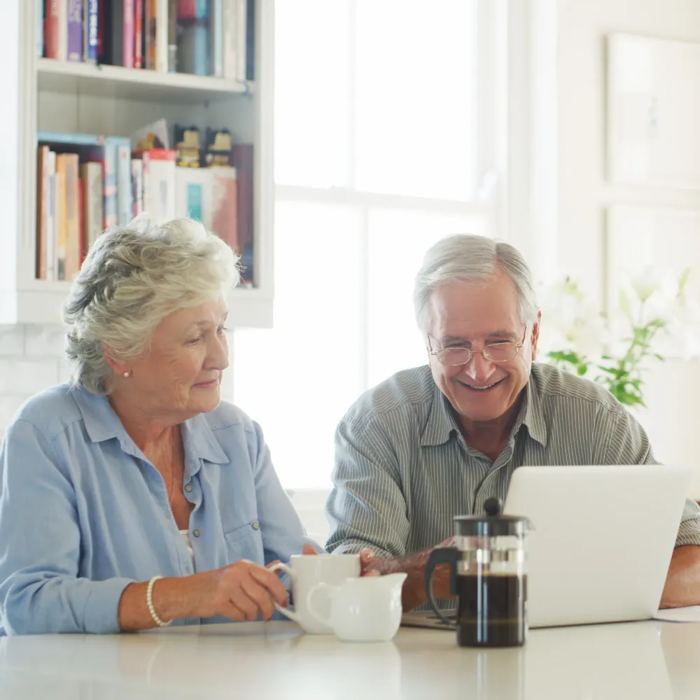 OE Services - A man and a woman are sitting at a table looking at a laptop.
