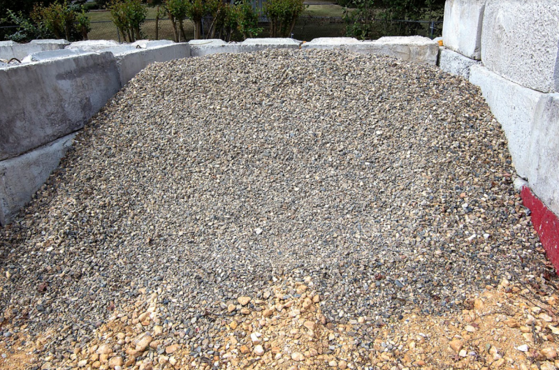 Large pile of gravel in a stone-walled area outdoors