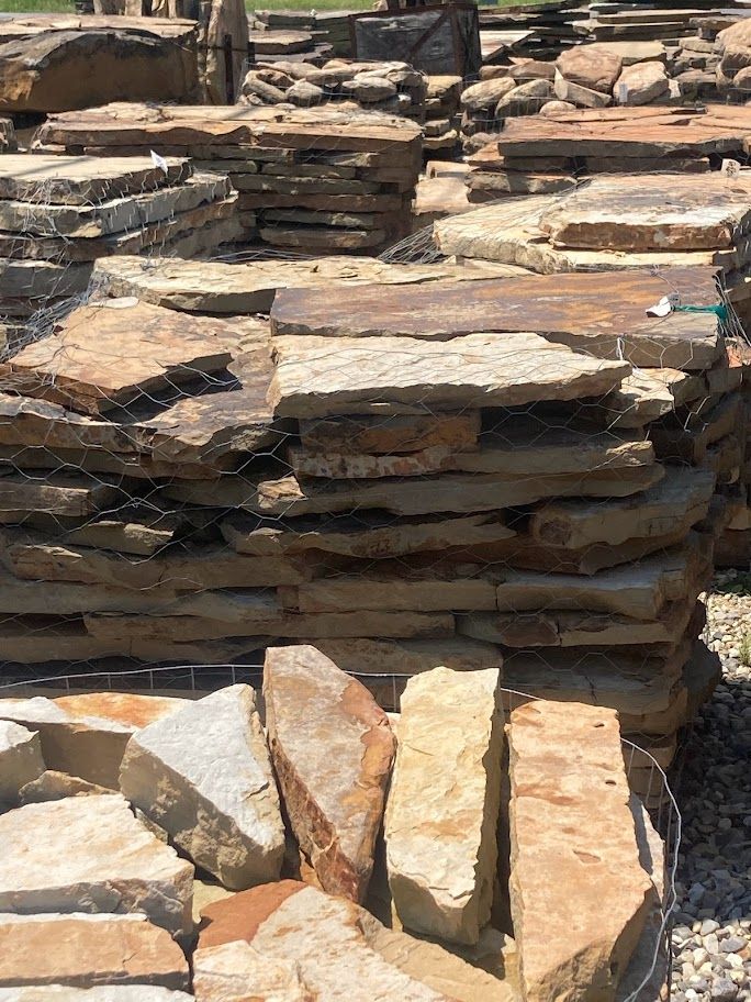 Stacked flat stones in tan and brown shades, piled in an outdoor setting.