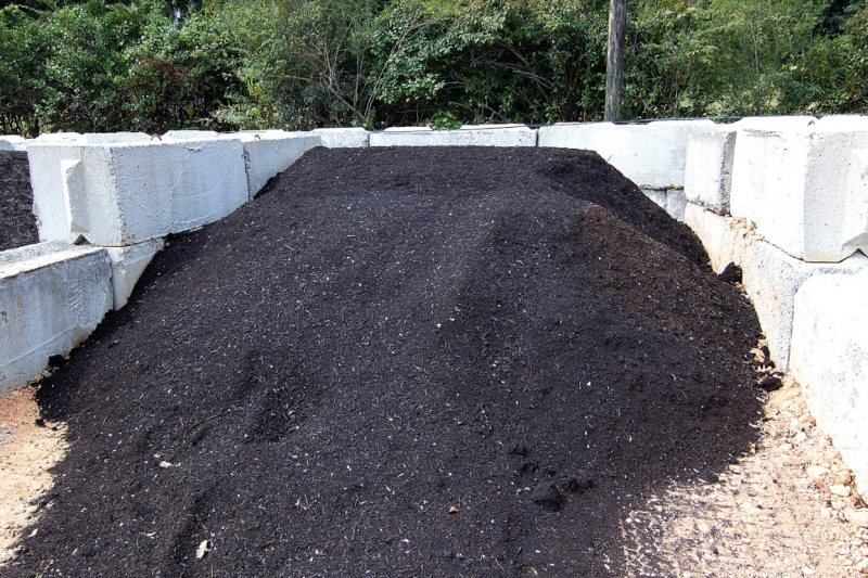 Large pile of black compost or soil between white concrete blocks outdoors