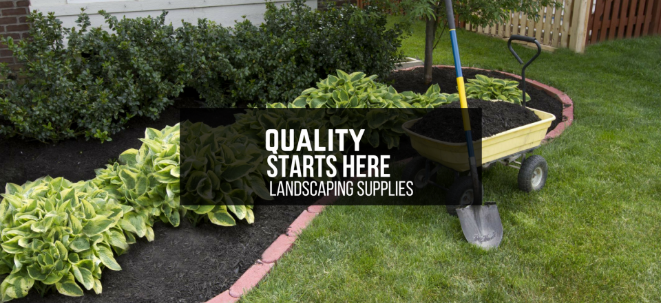 Garden trailer with mulch and shovel beside a lawn sign reading “Quality Starts Here Landscaping Supplies”