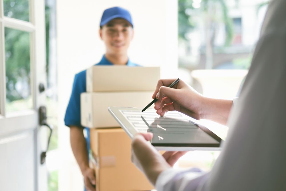 Delivery Worker Handing Over a Package While a Person Signs on a Clipboard — Access Couriers in Port Macquarie, NSW