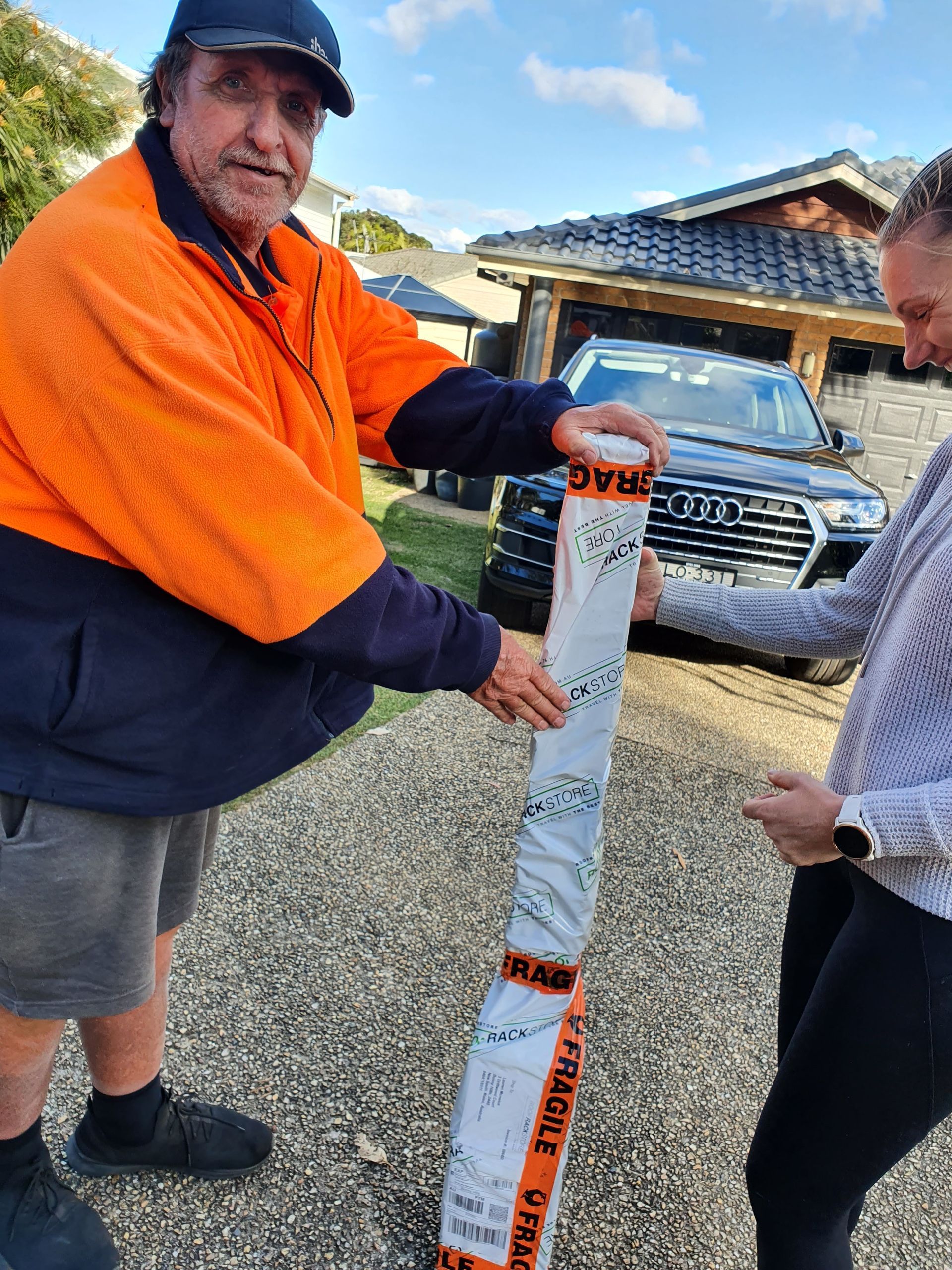 Two People Outdoors Holding a Tall Wrapped Package — Access Couriers in Port Macquarie, NSW