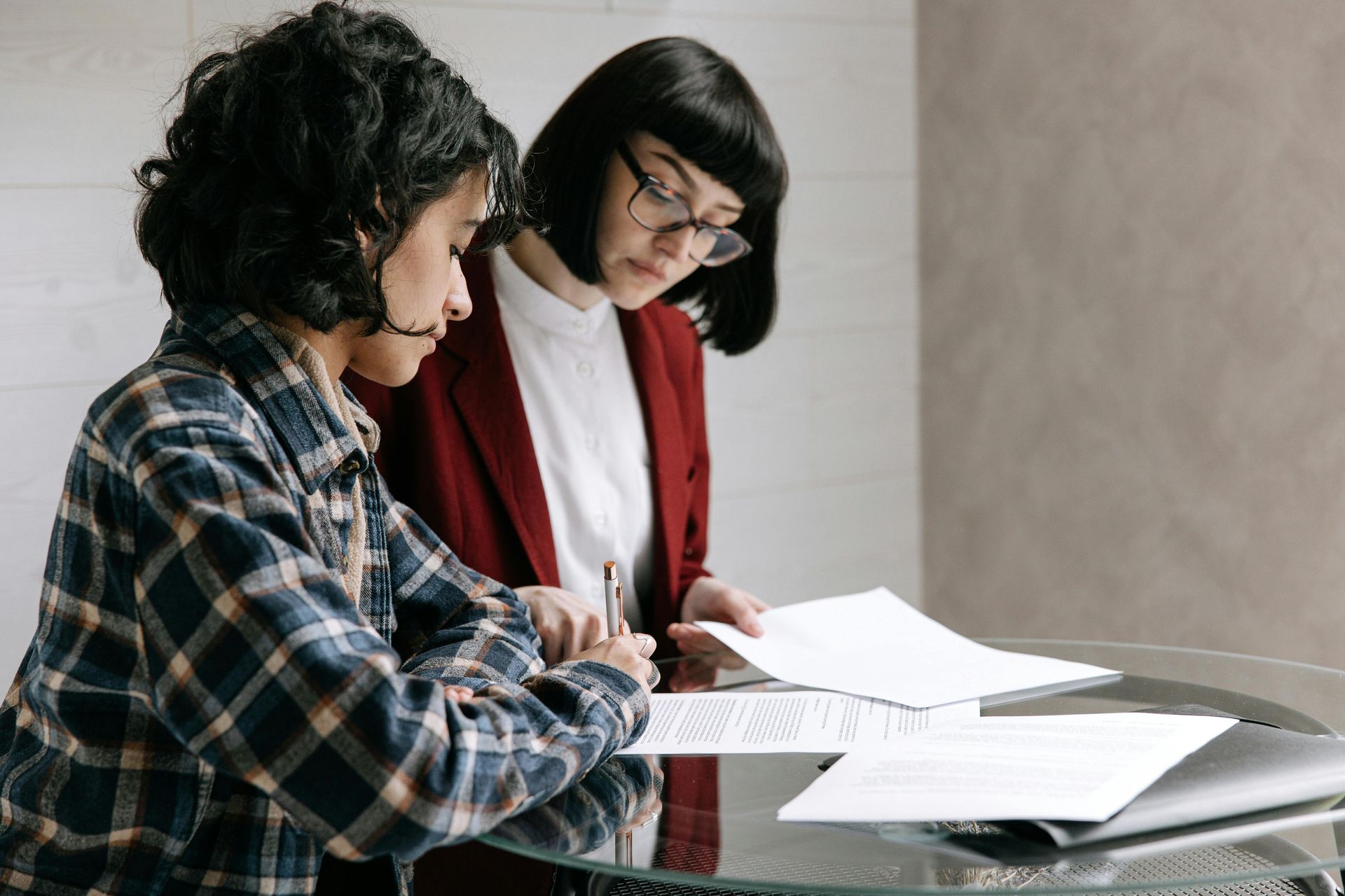 Two people review documents, one signs.