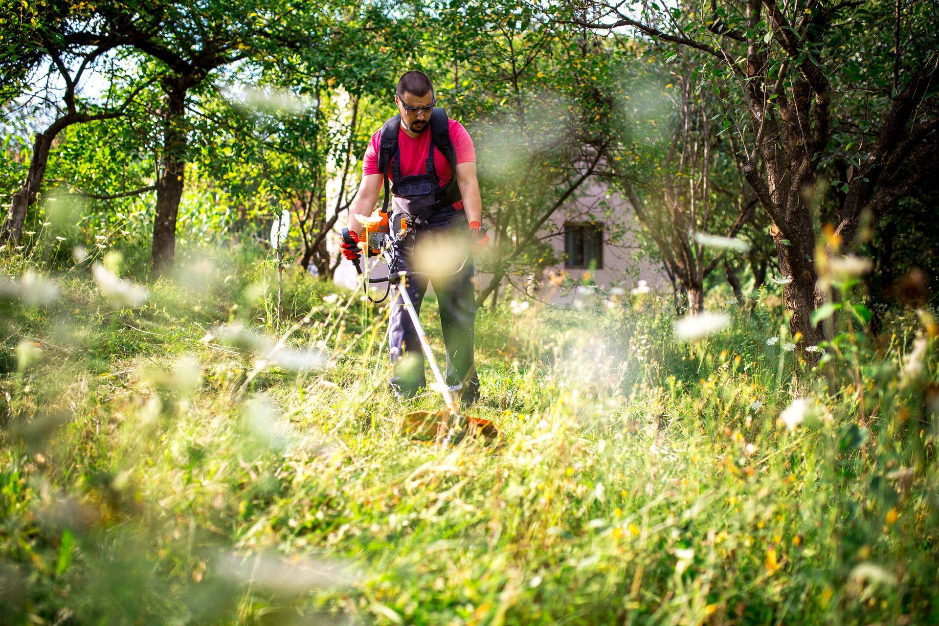 A man is mowing a lush green field with a lawn mower.