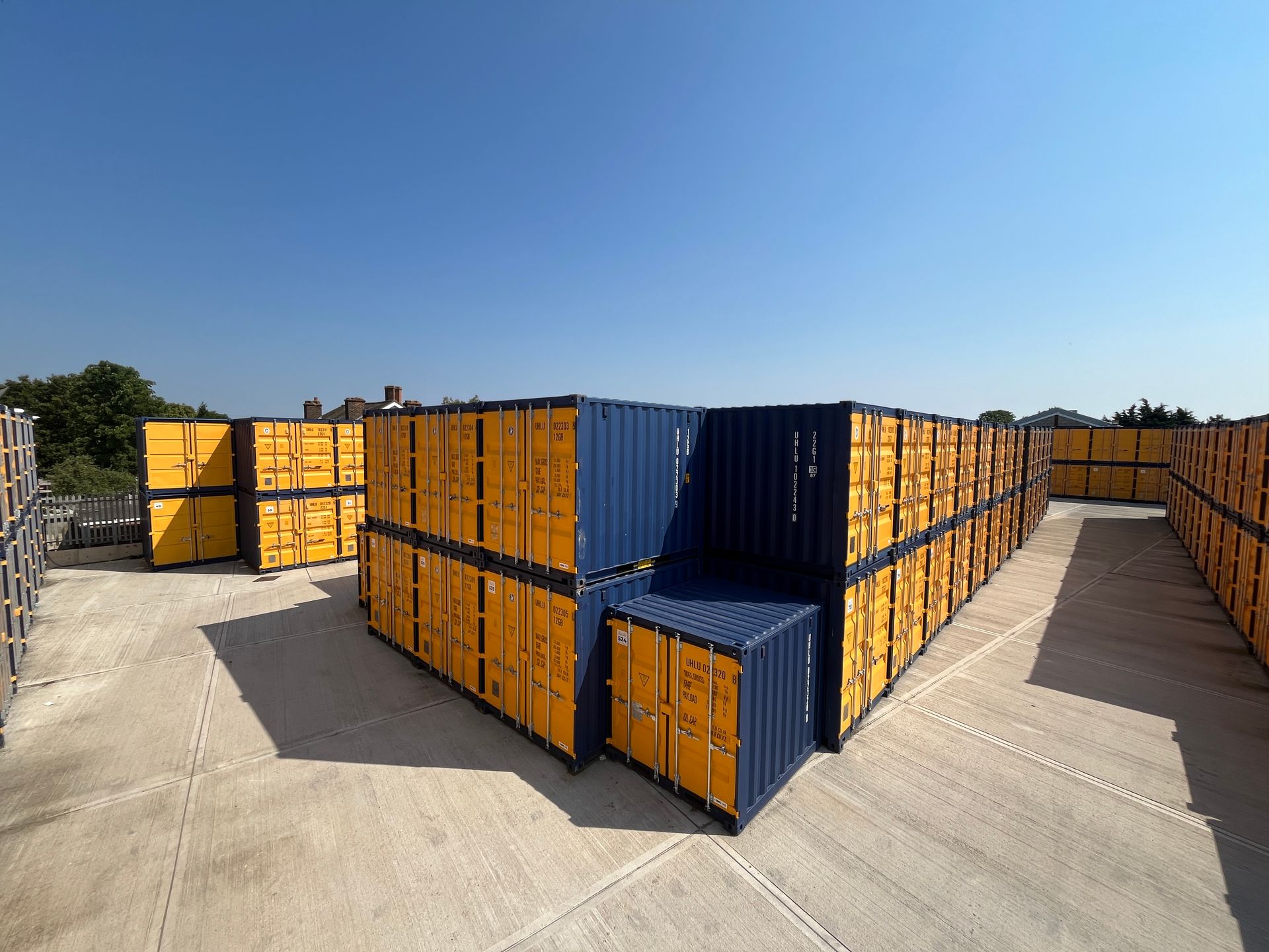A warehouse filled with lots of yellow and blue shipping containers.