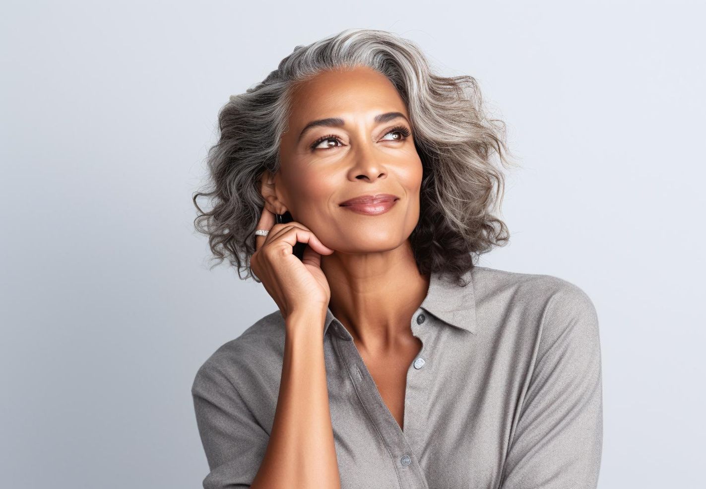 A woman with gray hair is smiling and looking up.