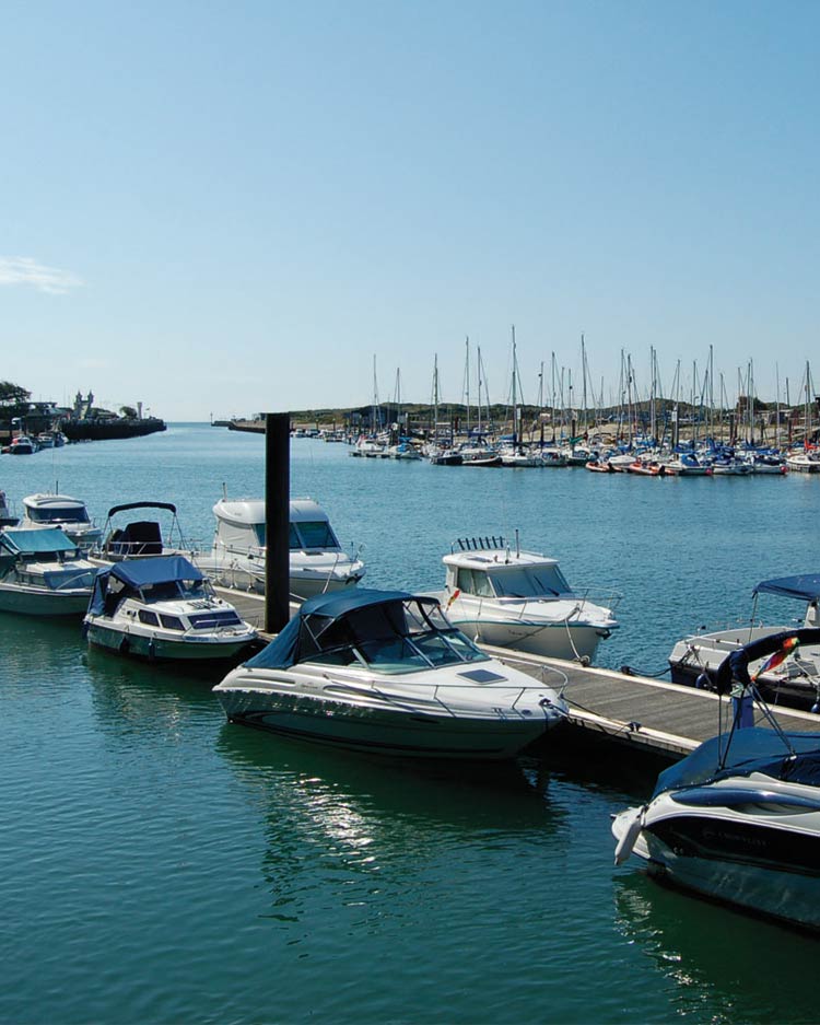 The River Arun harbour at Littlehampton Littlehampton Harbour. A view downriver towards the harbour mouth, with many small boats and yachts moored on the sparkling water.
