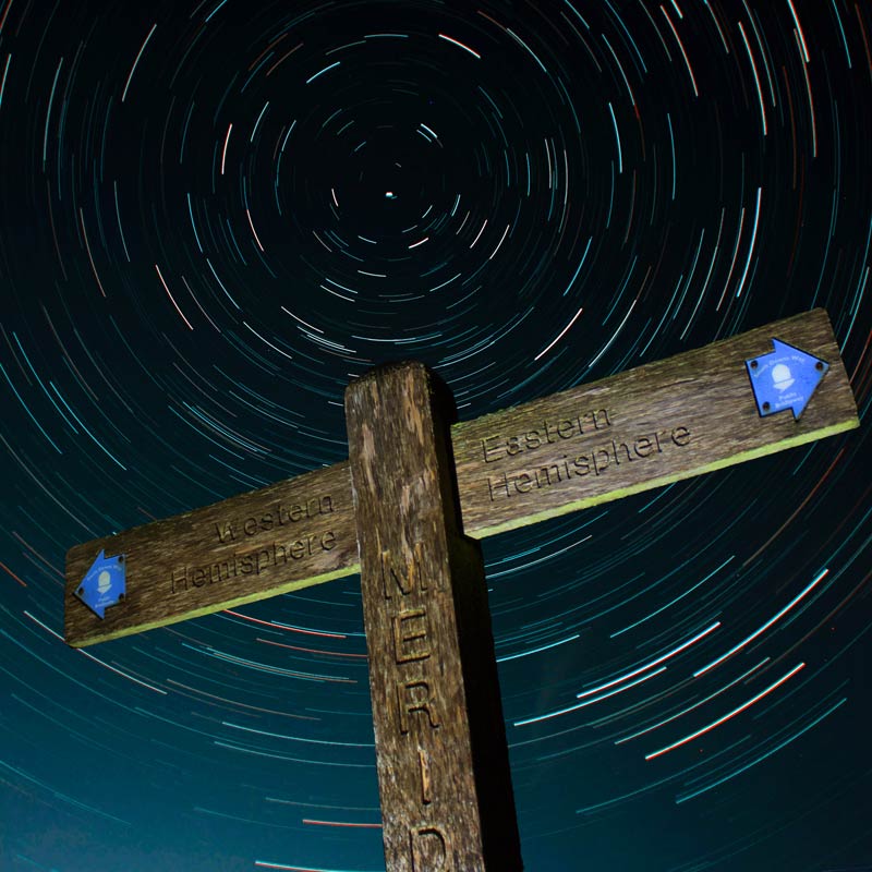 A wooden fingerpost for The South Downs Way against the  night sky and stars. The National Park has been awarded Dark Skies status.