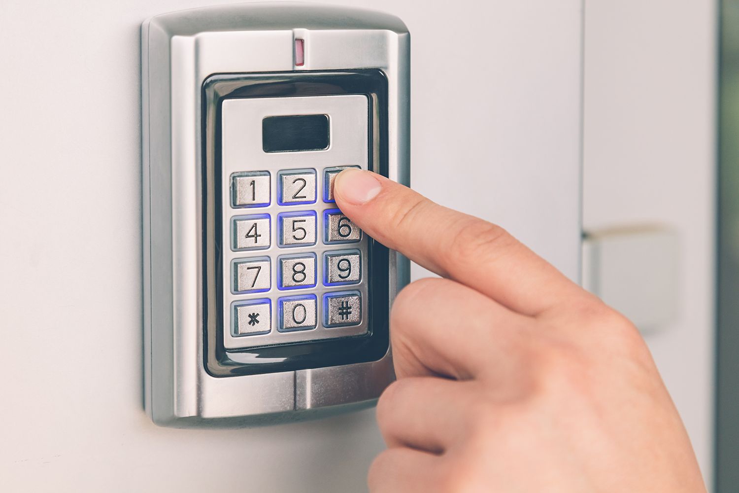 A hand is entering a security system code. A hand is entering a security system code.