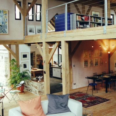 Loft-style living room with wood beams, white sofa, and open kitchen and dining area
