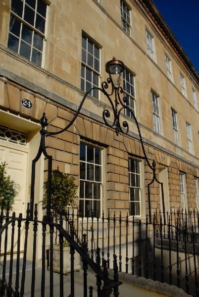 Stone building facade with wrought-iron sign and black fence in front