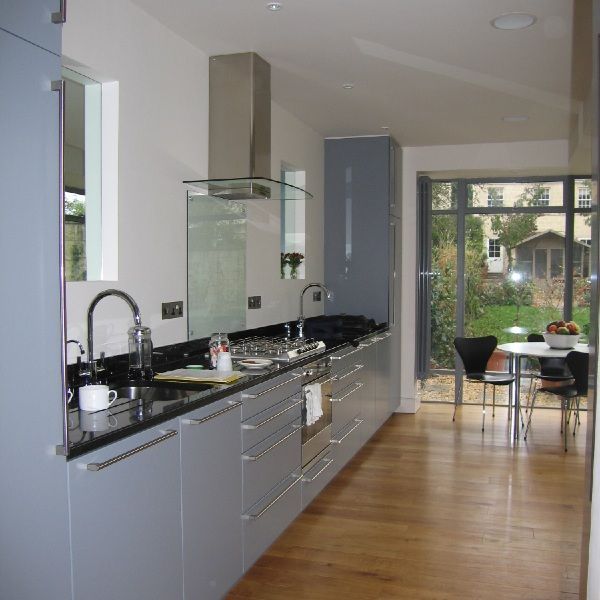 Modern kitchen with gray cabinets, black countertops, wooden floor, and dining area by a bright window.