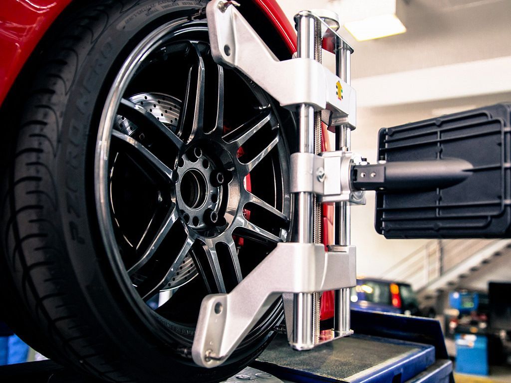 A car wheel is being aligned by a machine in a garage.
