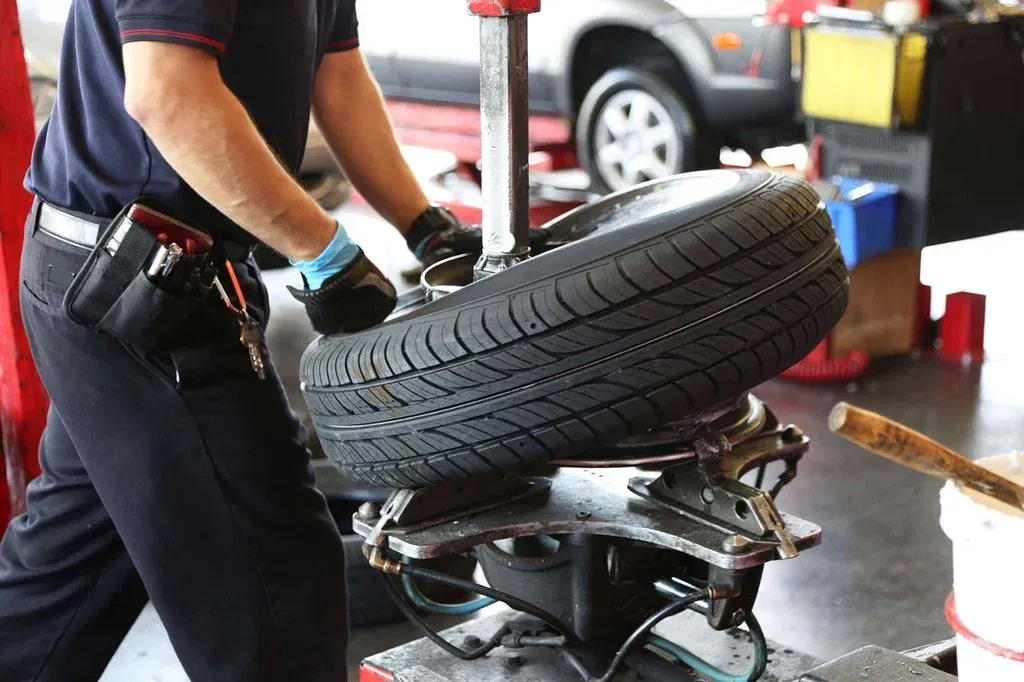 A man is changing a tire on a machine in a garage.