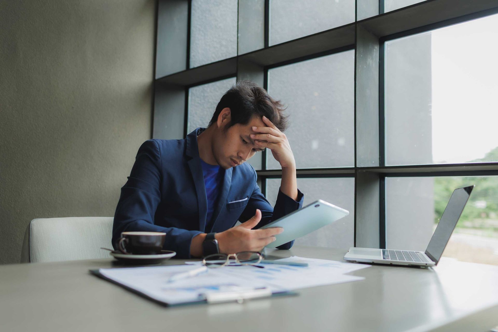 A man is holding a tablet, overwhelmed.