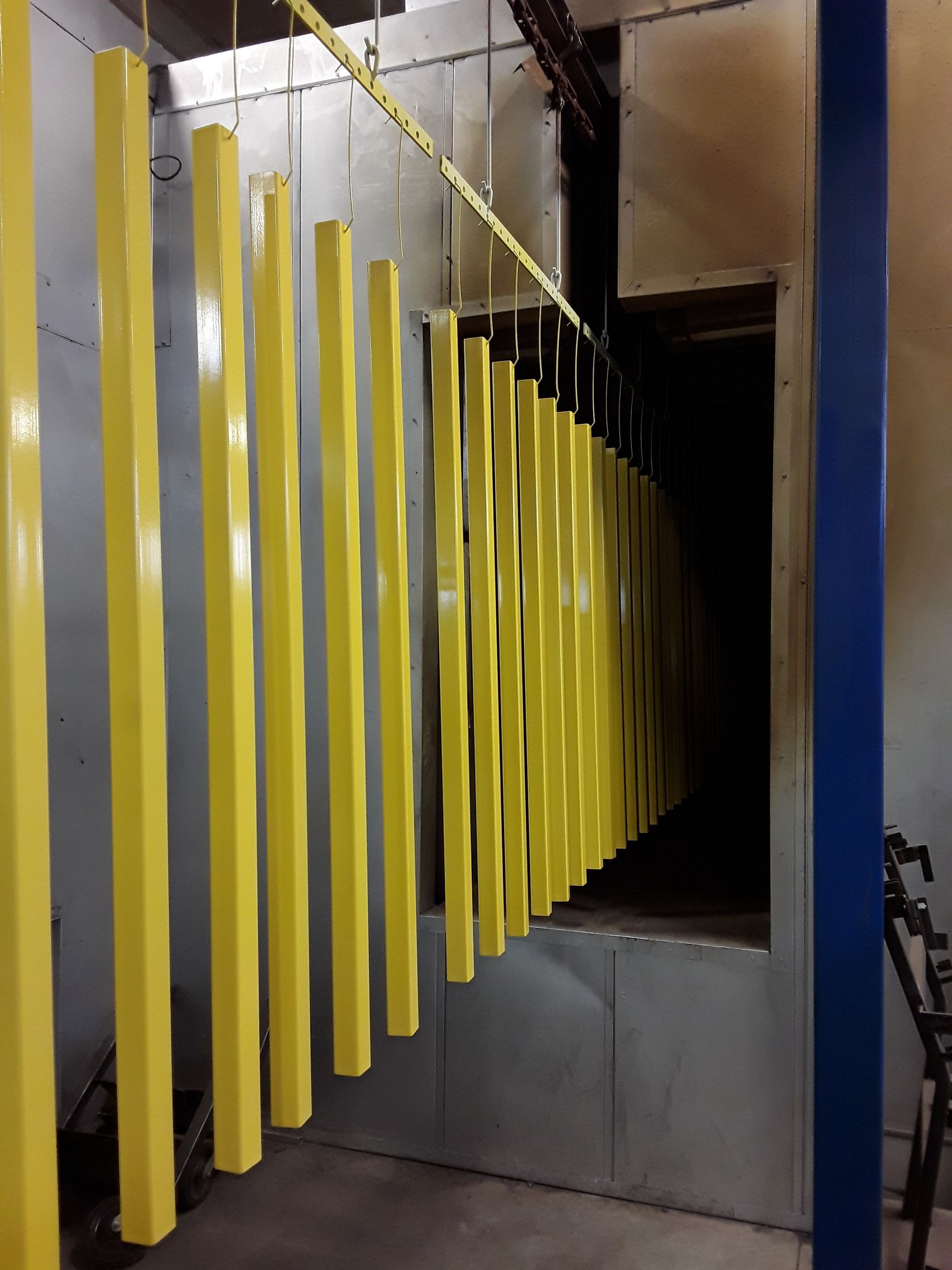 Yellow painted metal rods hanging inside an industrial oven.