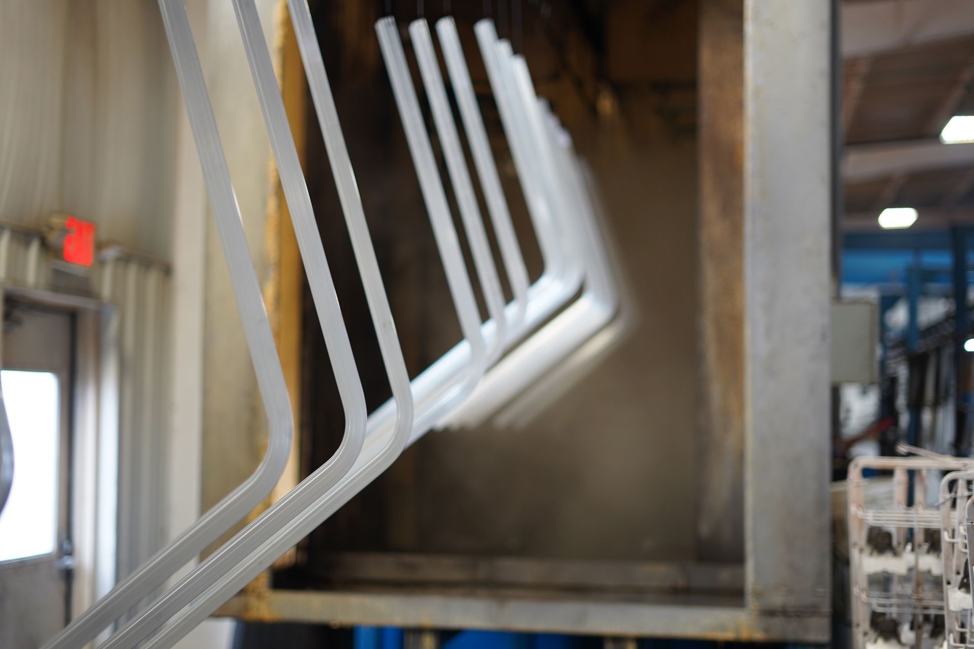 Metal chair frames hanging for powder coating in an industrial oven.