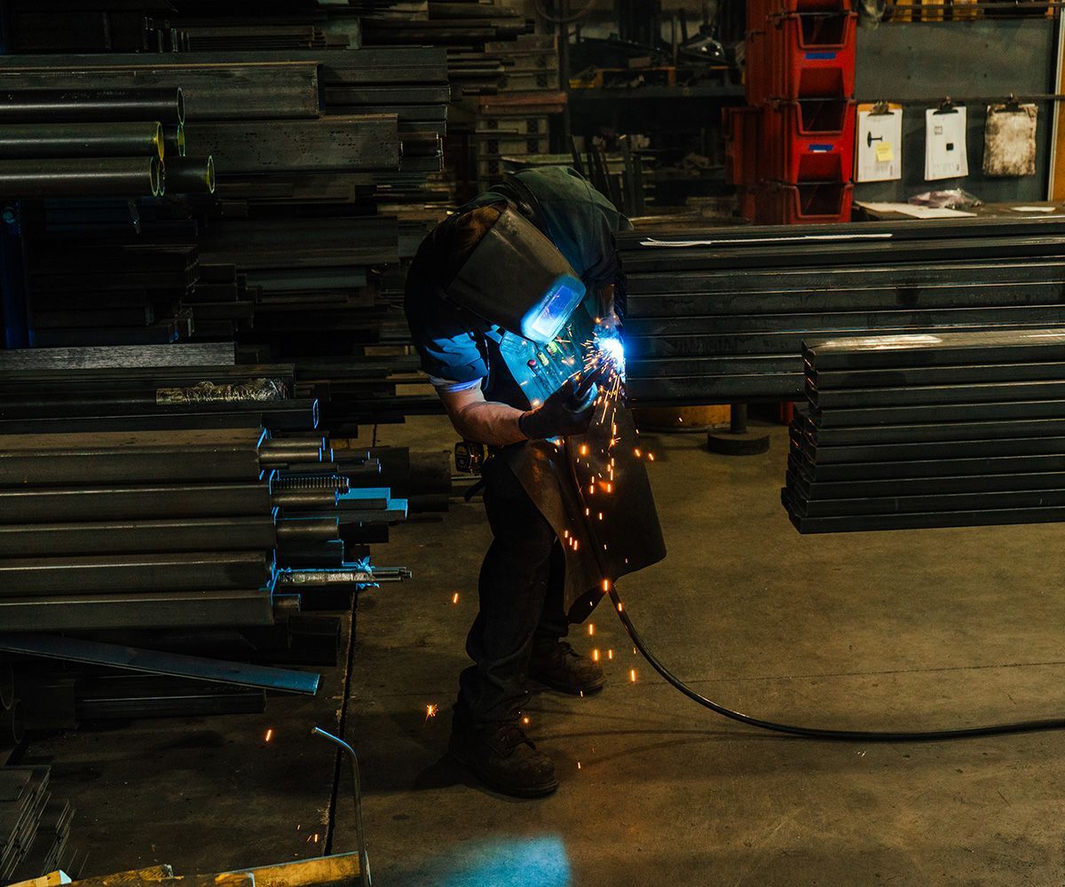 Welder in workshop, sparks flying, welding metal.