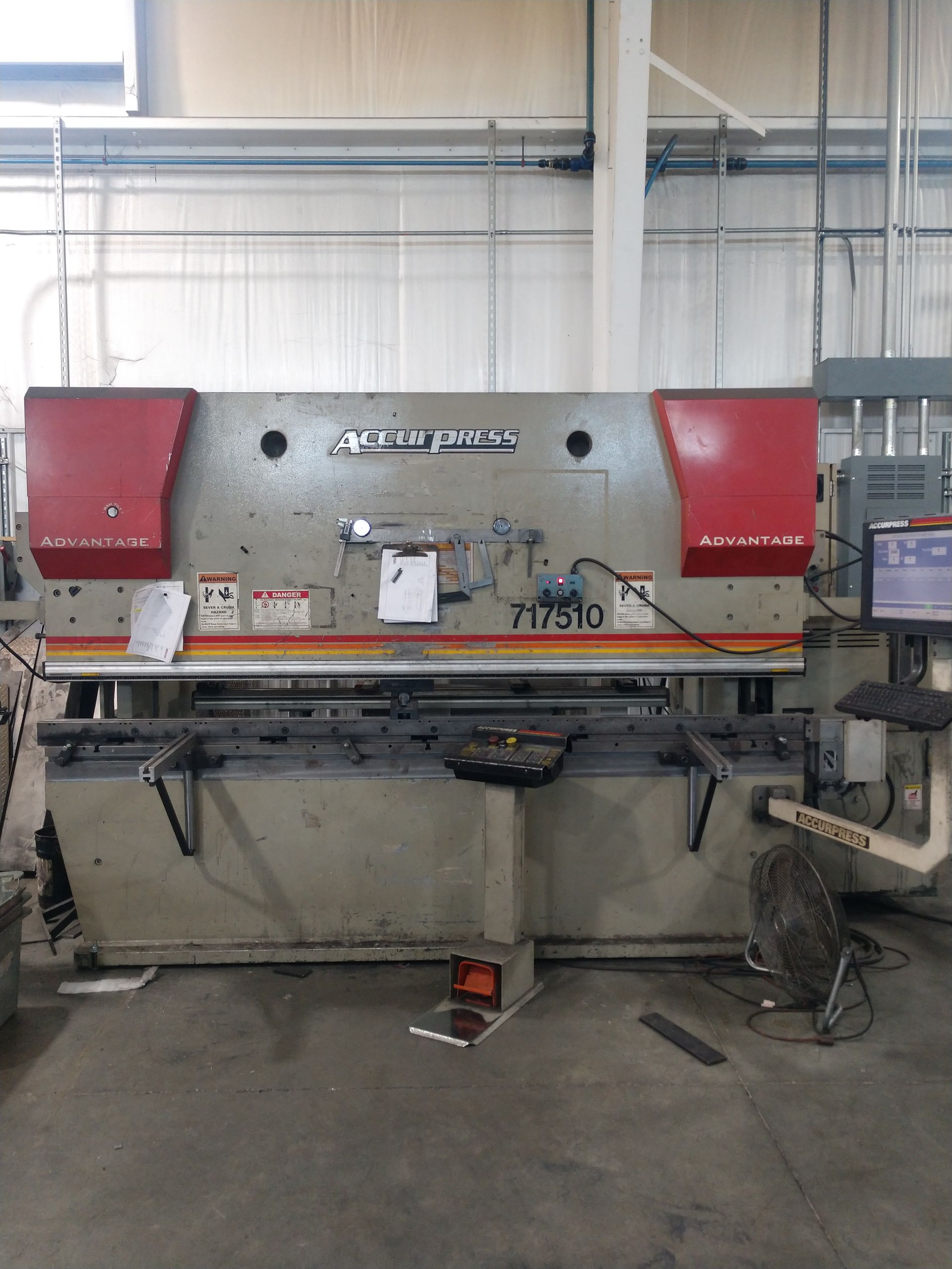 Large metal brake machine with red safety covers in a workshop.