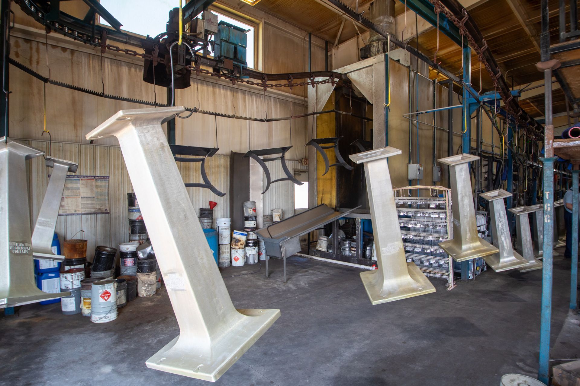 Large metal structures on an industrial assembly line, freshly painted, with machinery and paint cans visible.