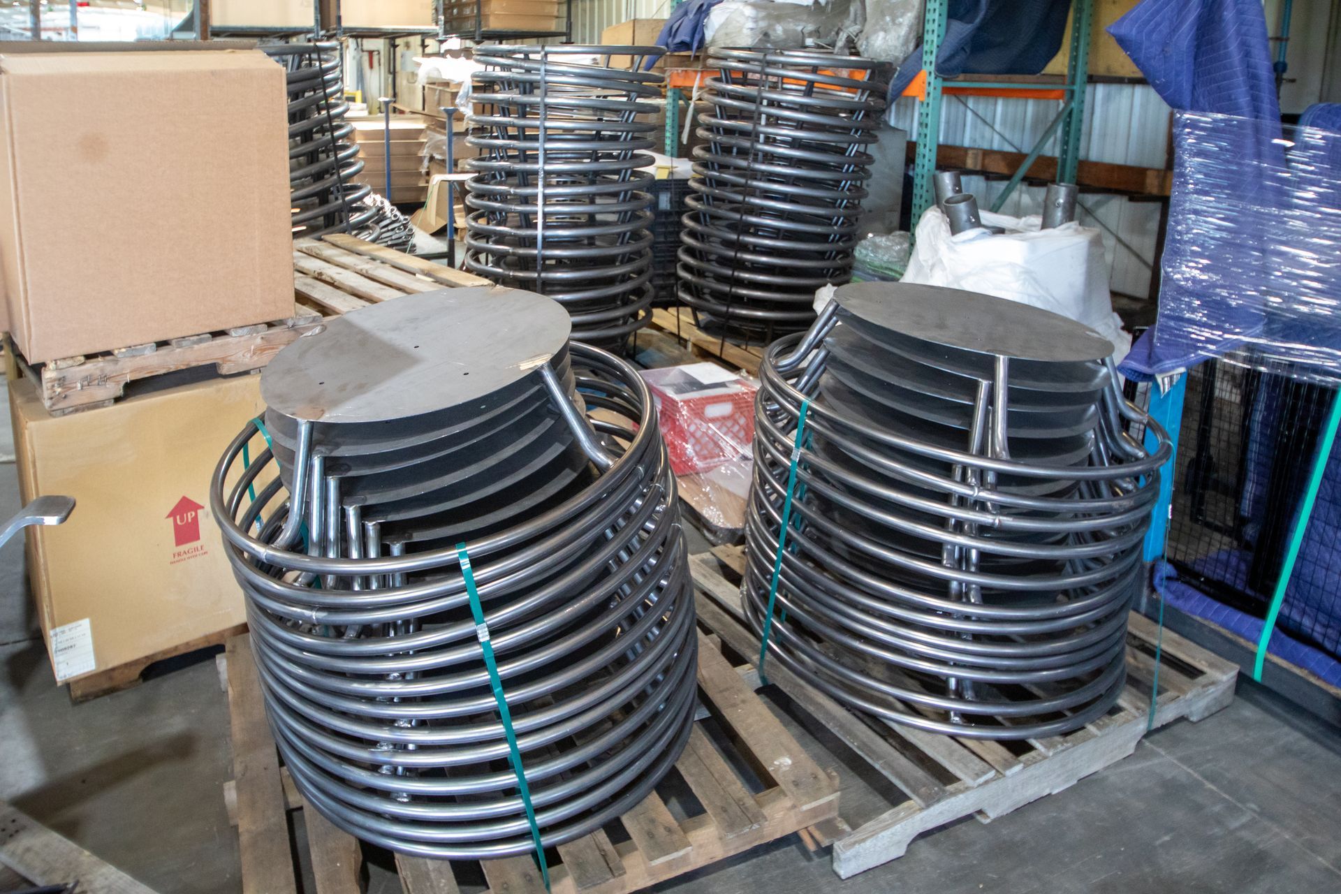Metal coil structures stacked on pallets in a warehouse setting.