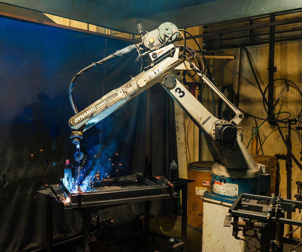 Welding robot in a workshop; sparks fly from the metal it is working on.