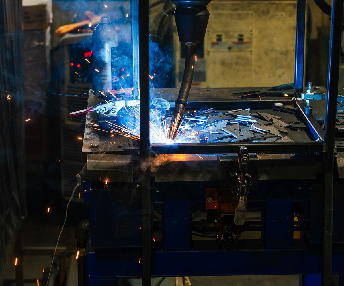Welding robot in workshop, welding metal with sparks and bright light.