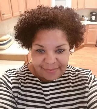 Person smiling in a kitchen, wearing a black-and-white striped shirt.