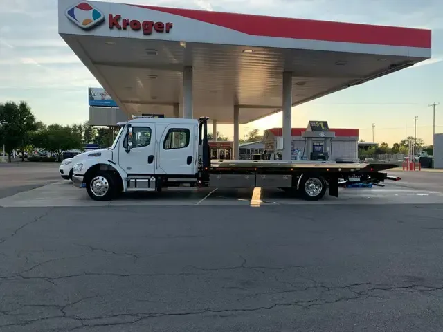 A tow truck is parked in front of a kroger gas station