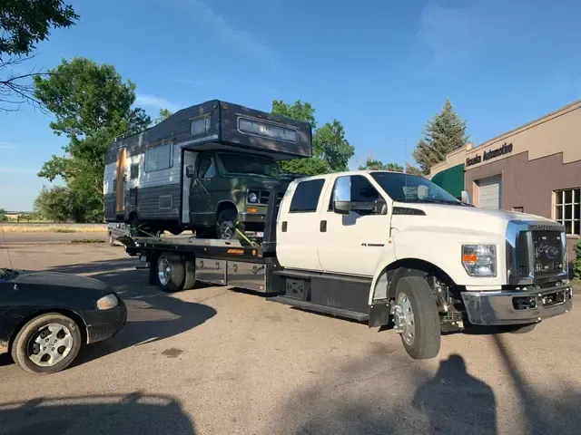 A tow truck is carrying a car and a trailer.