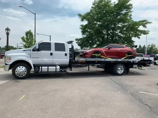 A red car is being towed by a tow truck.