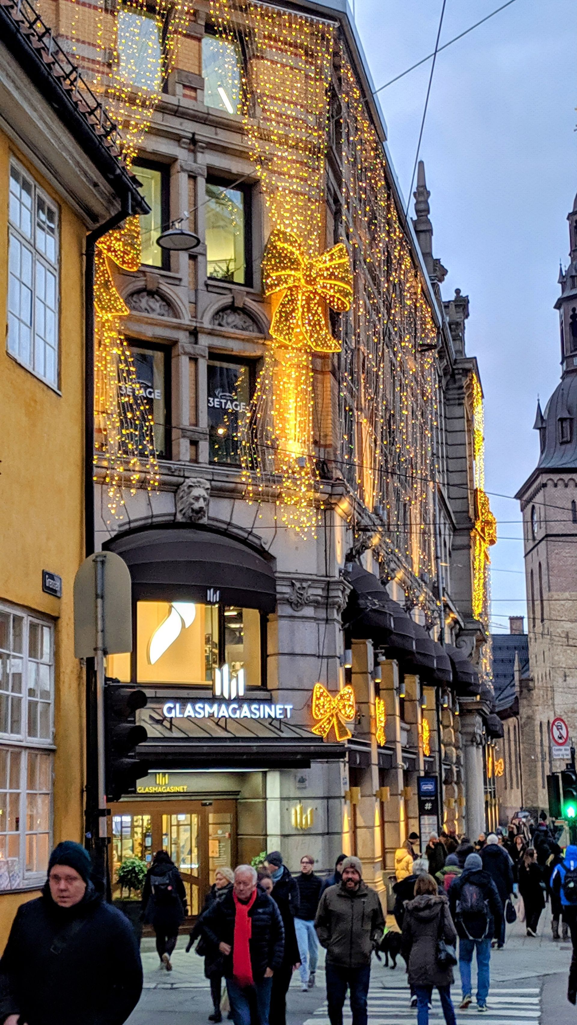 Oslo Christmas Mood. A festive illumination is featured by Glassmagasinet Trade Center with a group of Oslovians walking in the festive street.
