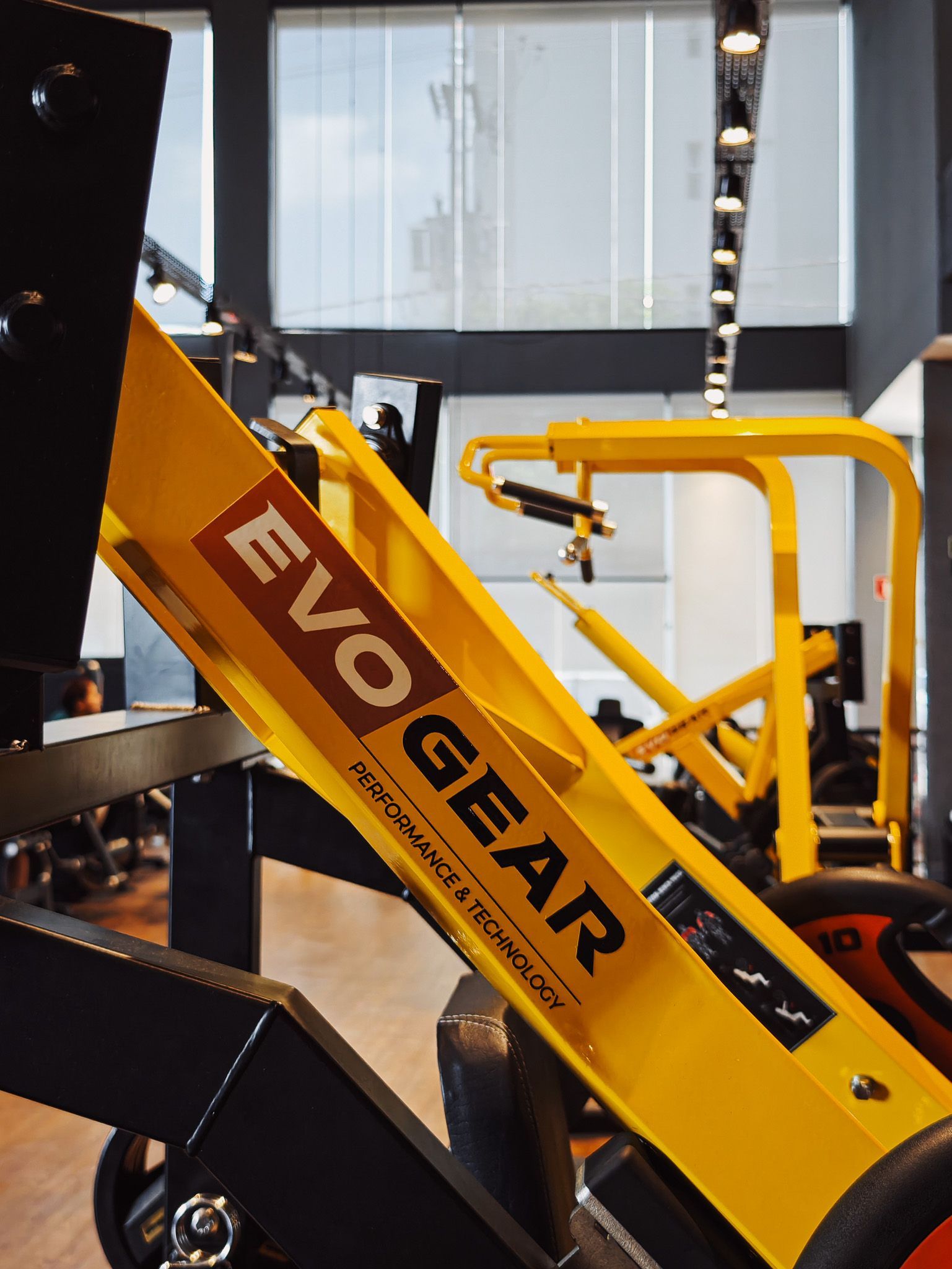 Máquina EVOGEAR amarela exposta em ambiente interno, com detalhes em preto e laranja.