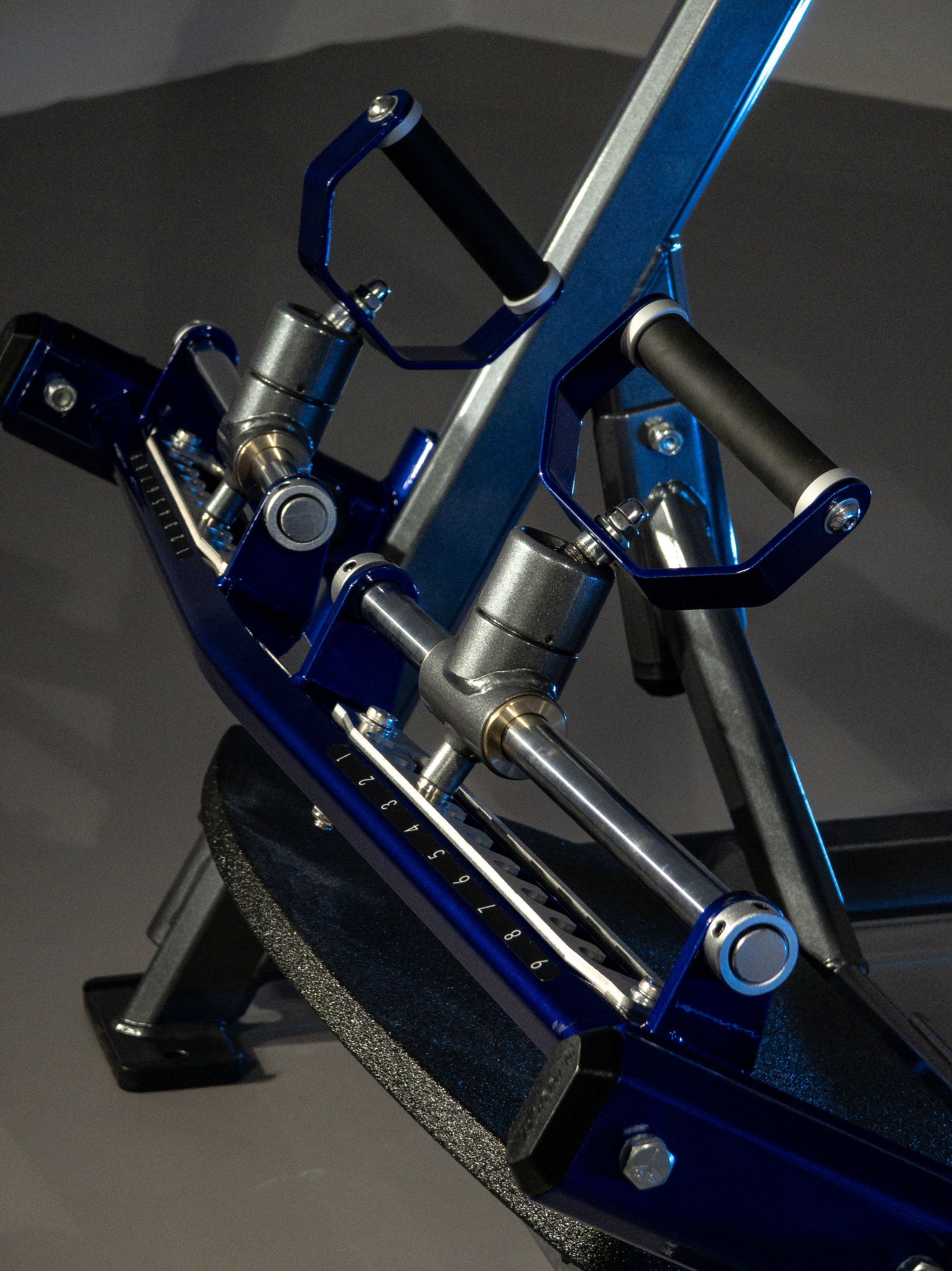 Conjunto mecânico de metal azul com molas e alavancas montado em uma superfície preta.