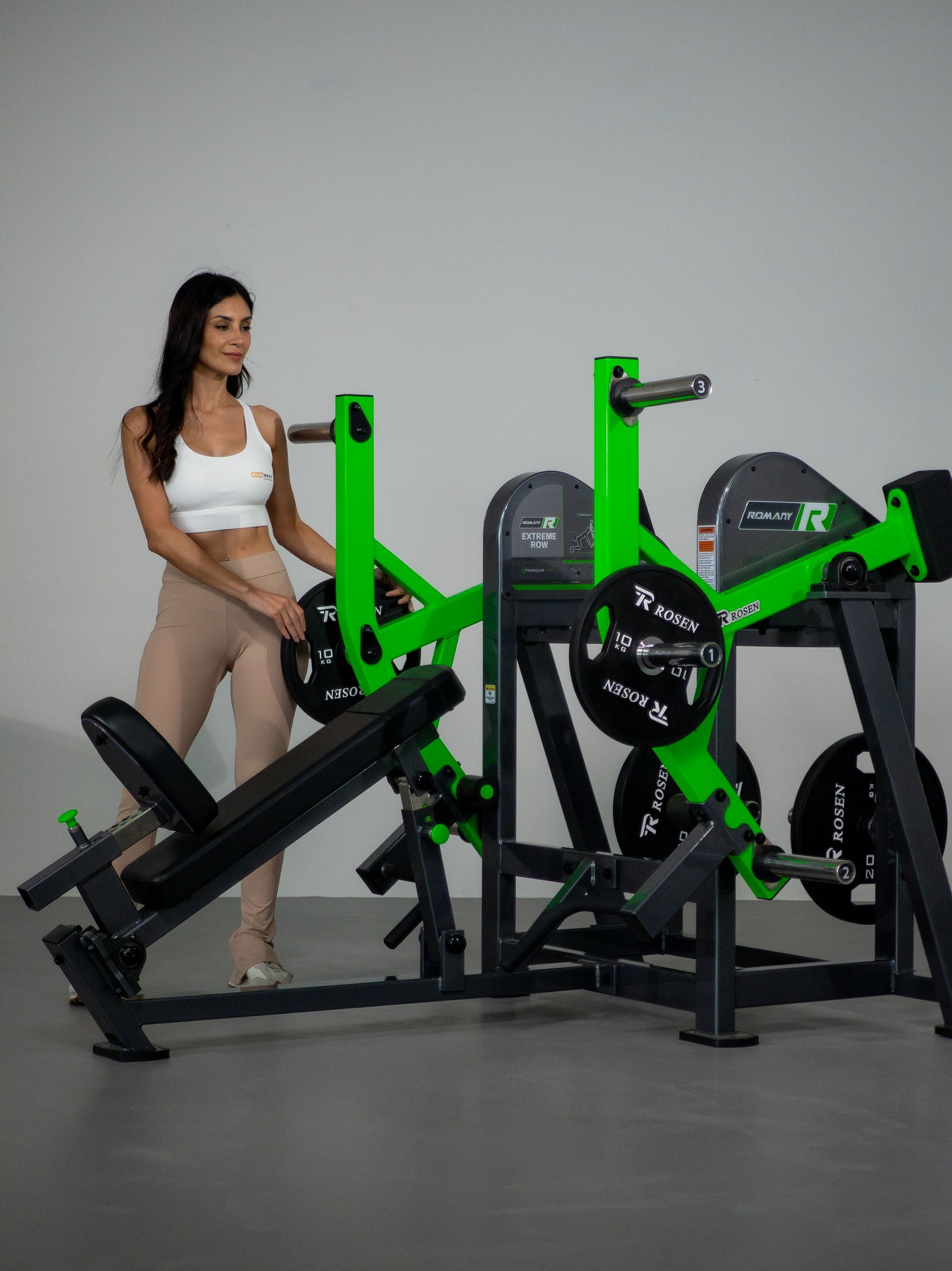 Mulher em pé ao lado de aparelhos de ginástica pretos e verde neon em um estúdio.
