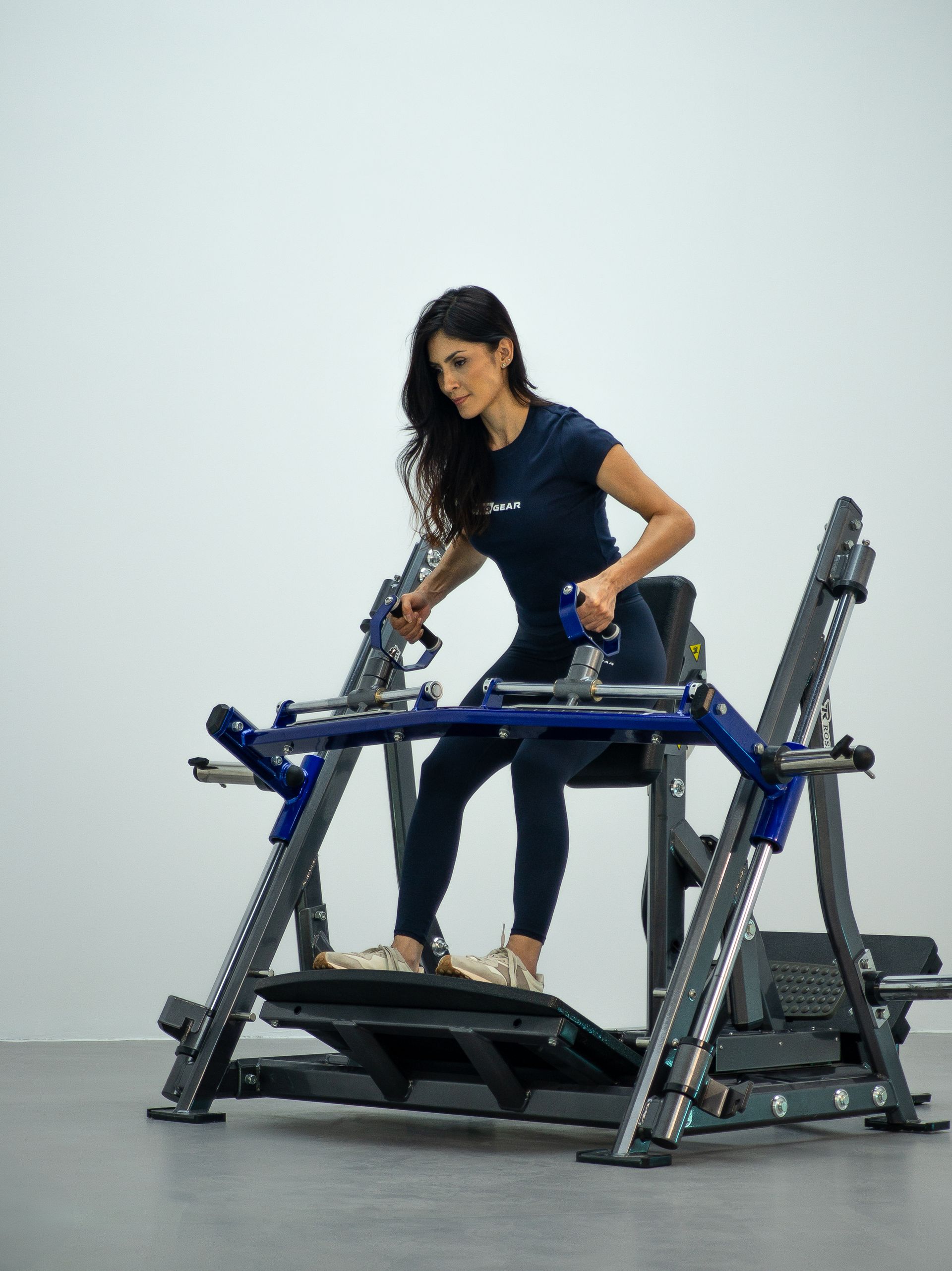 Mulher usando um aparelho de ginástica azul em um estúdio semelhante a uma academia.