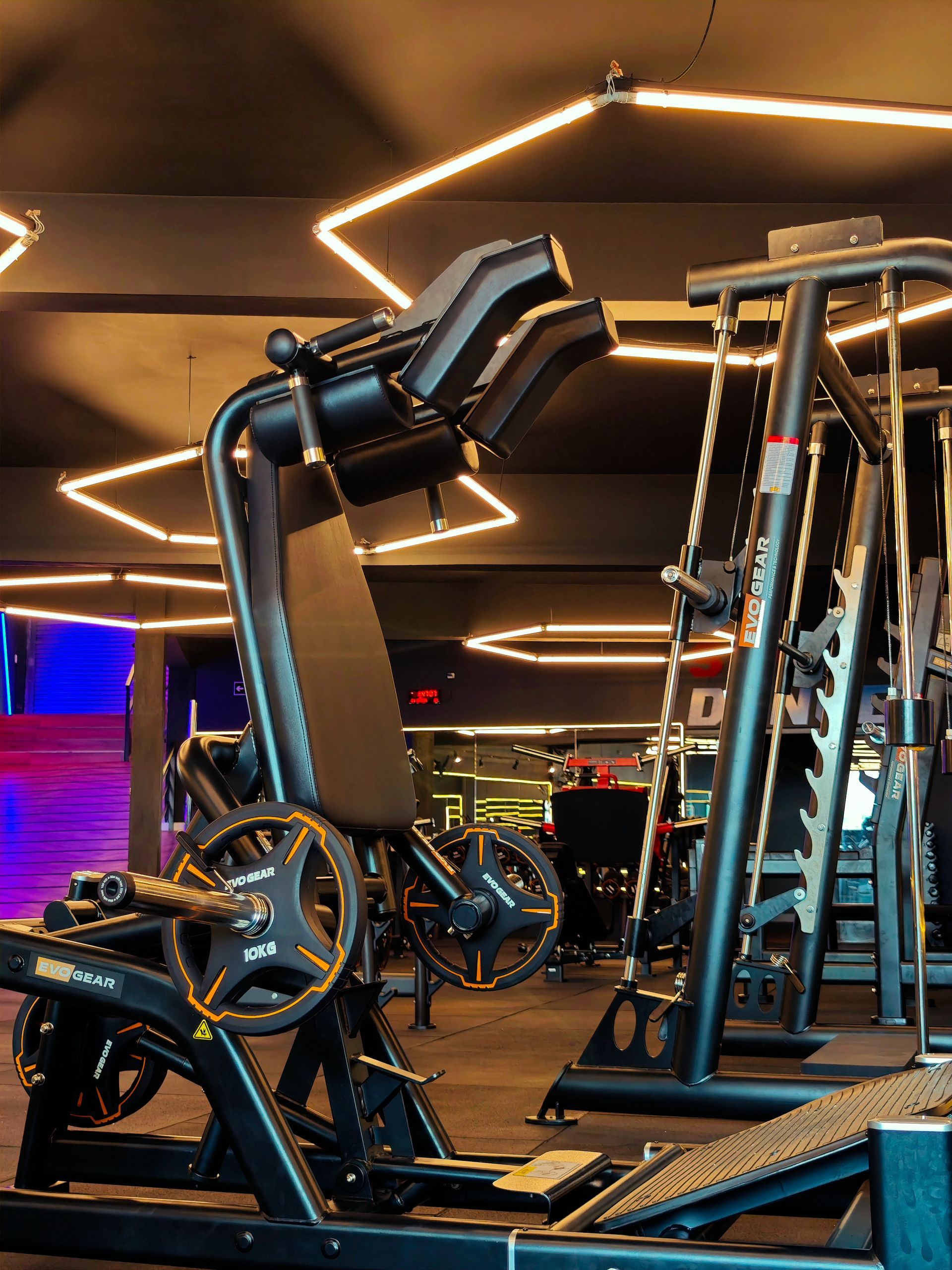 Uma academia com muitos equipamentos de exercícios e luzes no teto.