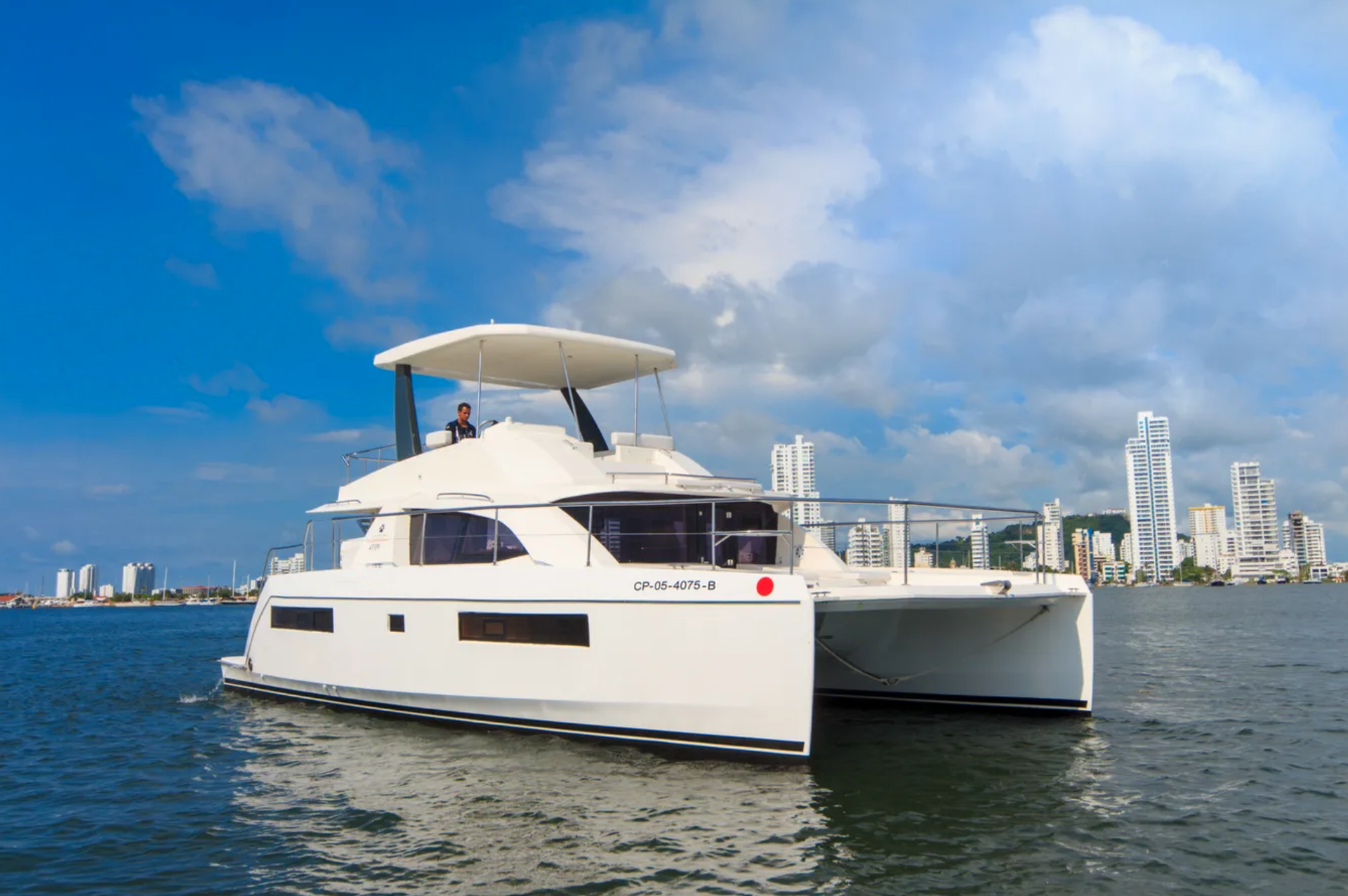 A white catamaran is floating on top of a body of water.