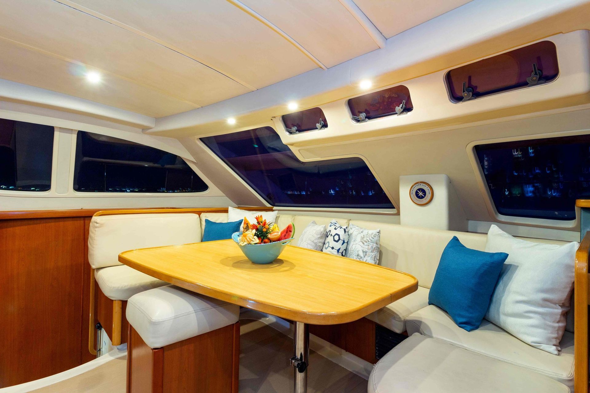 A dining room on a boat with a wooden table and blue pillows.