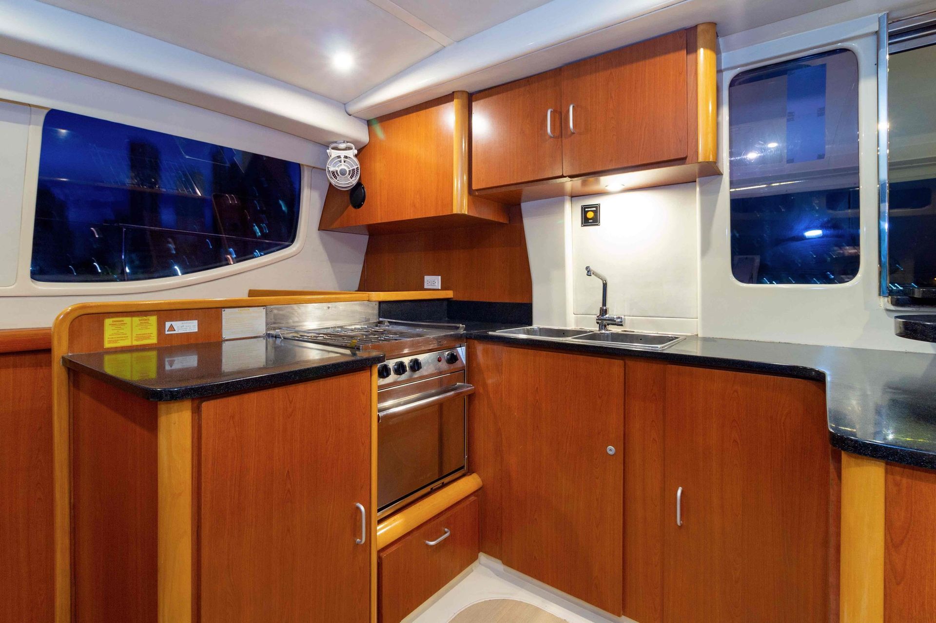 A kitchen on a boat with wooden cabinets and black counter tops