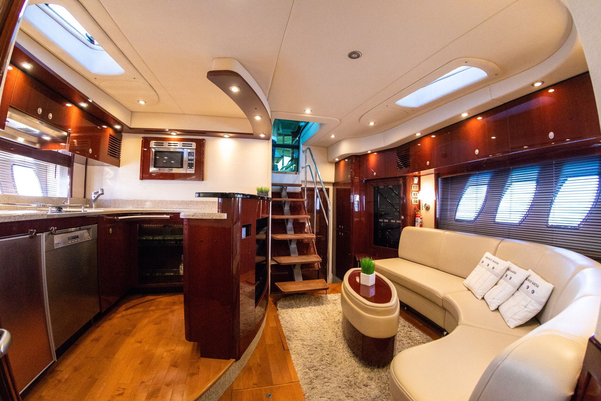 A living room and kitchen on a boat with a couch and stairs.