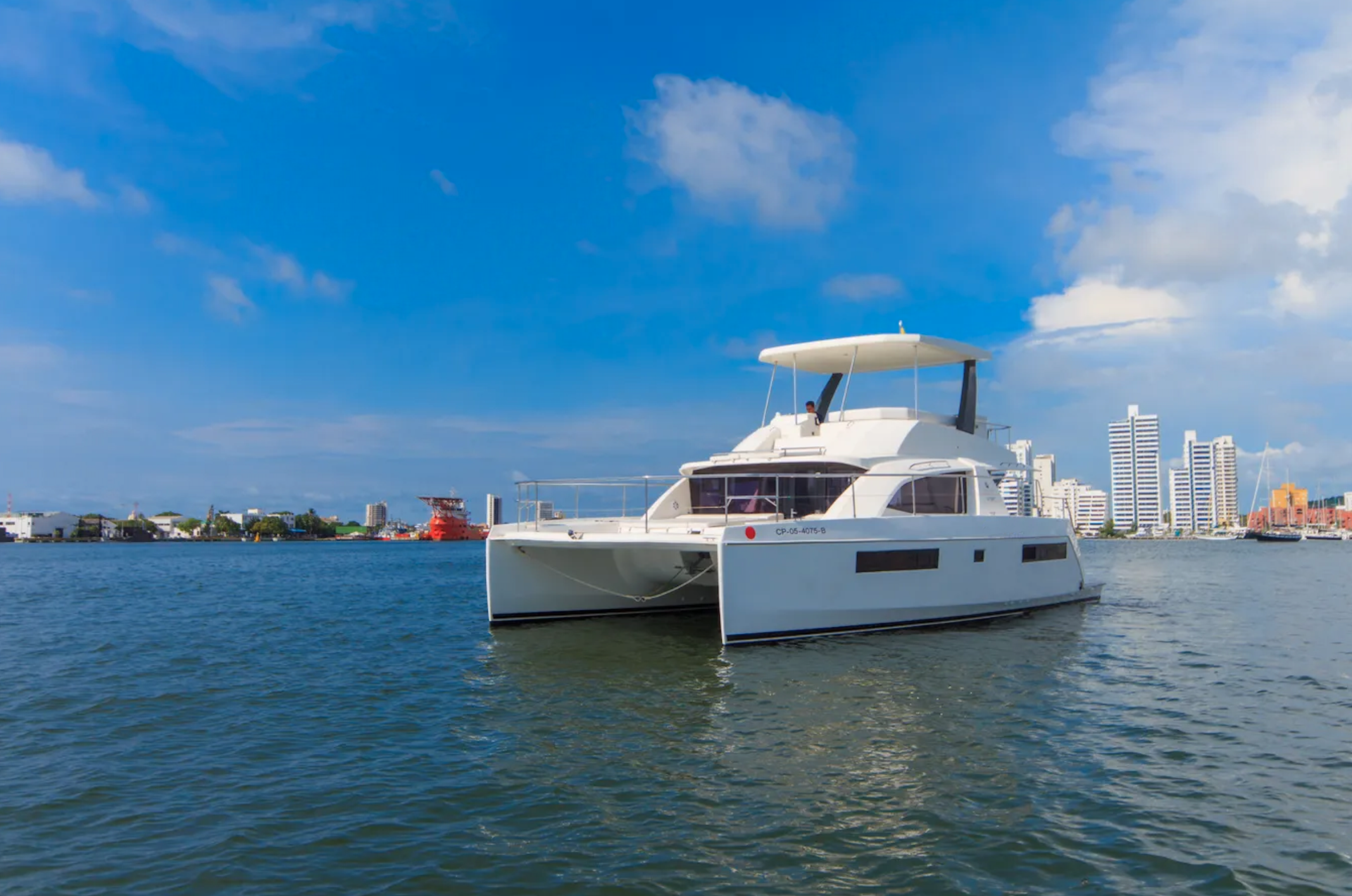A white catamaran is floating on top of a body of water.