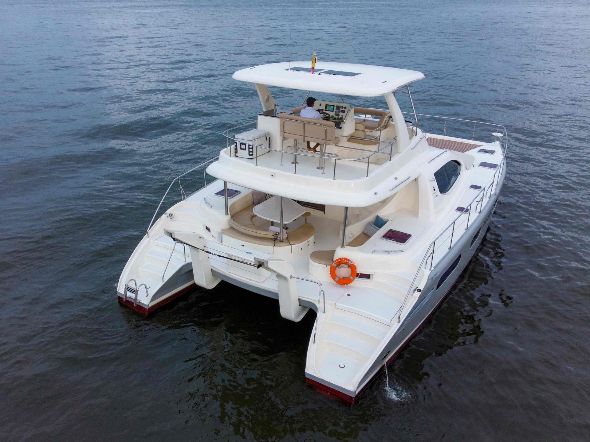 A white catamaran is floating on top of a body of water.