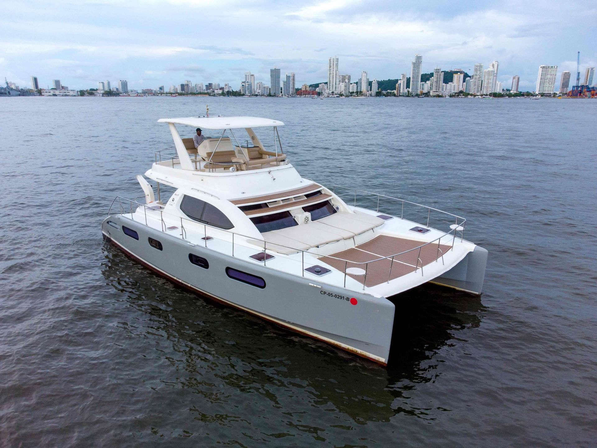 A white catamaran is floating on top of a body of water.